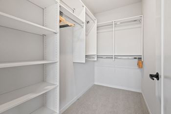 a walk in closet with white shelves and a white closet door